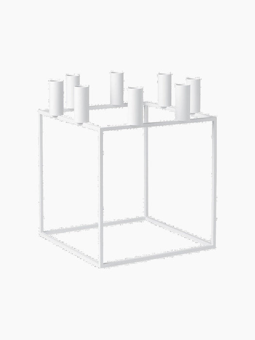 The white Kubus 8 candle holder, a minimalist cube-shaped frame with holders for eight candles, viewed from an angle.