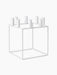 The white Kubus 8 candle holder, a minimalist cube-shaped frame with holders for eight candles, viewed from an angle.