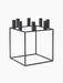 The black metal Kubus 8 candle holder, a minimalist cube frame with eight cylindrical holders for candles.