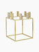 The gold-plated Kubus 8 candle holder, shown from an angle. It has a square, minimalist frame with 8 candle sockets on top.