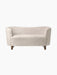 Front view of the Mingle Sofa in Moonlight sheepskin, with a curved back and dark stained oak legs on a black background.