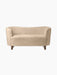 A front view of the Mingle Sofa, upholstered in Honey-coloured sheepskin, with dark stained oak legs, on a black background.