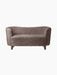 A front view of the Mingle Sofa, upholstered in Sahara-coloured sheepskin, with a curved back and dark-stained oak legs.
