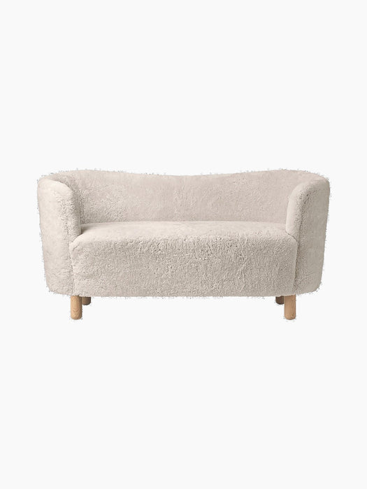A front view of the Mingle Sofa in off-white Moonlight sheepskin with a curved back, rounded arms, and natural oak legs.