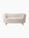 A front view of the Mingle Sofa in off-white Moonlight sheepskin with a curved back, rounded arms, and natural oak legs.