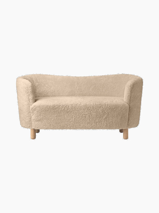 Front view of the Mingle Sofa in honey sheepskin. The compact two-seater has curved arms and rests on four natural oak legs.