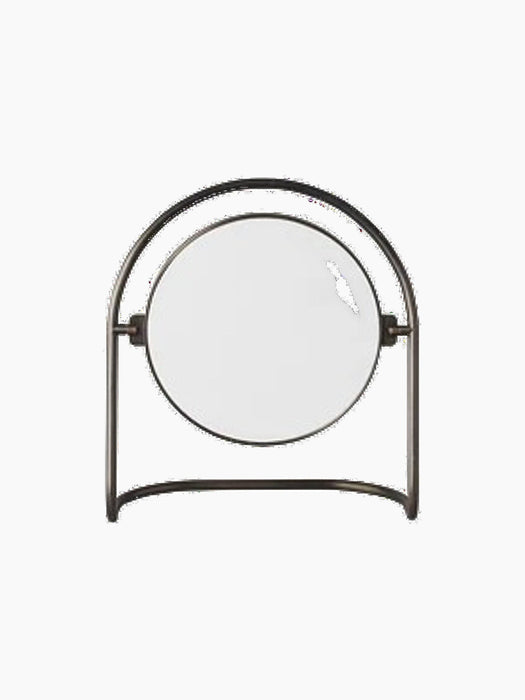 Front view of the Nimbus Table Mirror. A round mirror is suspended and pivots within a U-shaped stand made of bronzed brass.
