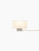 Front view of the illuminated Nonna Table Lamp with its rectangular, sand-coloured shade and brushed aluminium base.