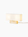 Angled view of the Nonna Table Lamp in Travertine, illuminated to show its rectangular stone base and long, fabric lampshade.