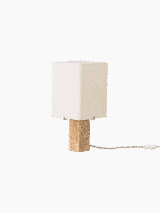 Angled view of the Nonna Table Lamp, off. It features a rectangular travertine base and a square, sand-hued shade.