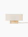 Front view of the Nonna Table Lamp with a rectangular travertine base and a wide, sand-coloured linen lampshade.