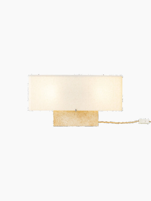 Front view of the wide Nonna Table Lamp in Travertine, featuring an illuminated rectangular sand-coloured shade on a base.