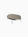 The small NoNo Table with a beige oval glass top and slender black powder-coated steel legs, shown on a black background.
