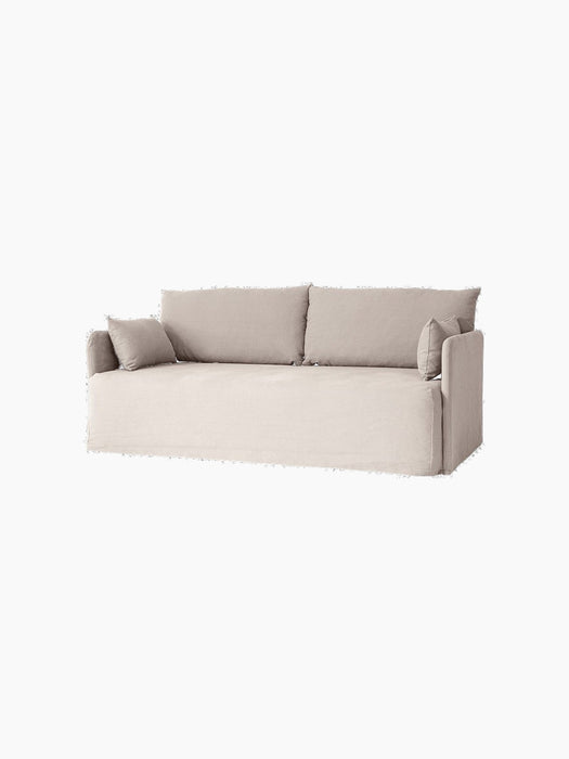 Angled view of the Offset Sofa w. Loose Cover in a light grey fabric, with two large back and two smaller side cushions.