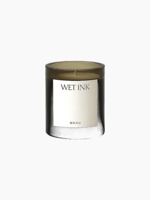 The Olfacte Scented Candle in Wet Ink, in a dark smoked glass jar with a minimalist white label on a black background.