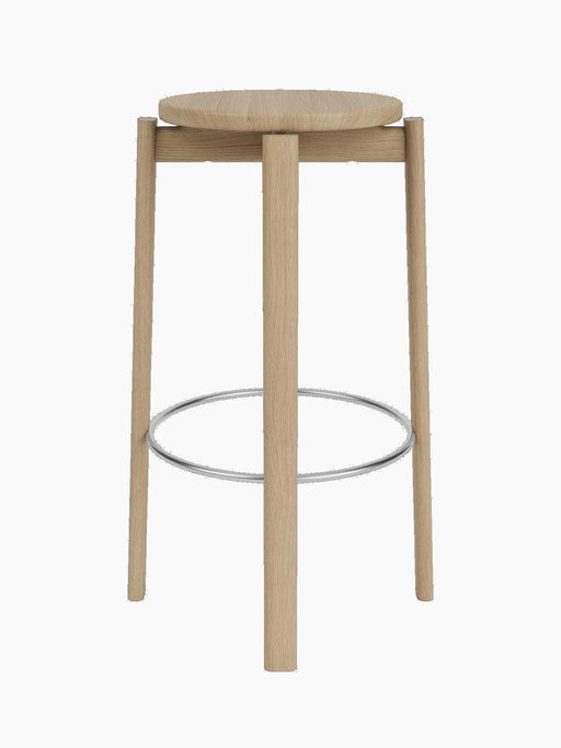 A front-on view of the Passage Bar Stool in natural oak, featuring a round seat, four legs, and a stainless steel footring.