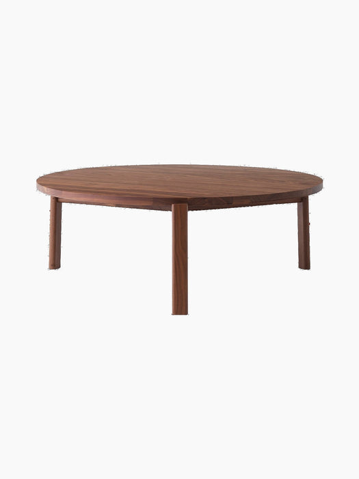 A front-facing image of the Passage Lounge Table in walnut. The round, wooden coffee table has four legs and a smooth finish.