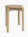 A Passage Stool with a round seat in natural oak, shown from a three-quarters angle against a black background.