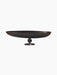 Front view of the Relevé Platter in black wood, showcasing its wide, shallow oval shape atop a short, sculpted pedestal base.