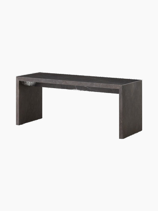 An angled shot of the Plinth Bridge in Grey Kendzo. It is a long, low, rectangular bench made of dark grey veined marble.