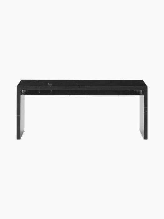 A front-facing view of the Plinth Bridge in Nero Marquina, a long, low bench made of black marble on a black background.