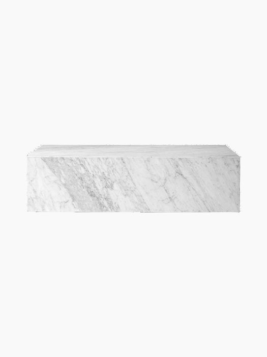 Front view of the Plinth Low, a rectangular podium made of white Carrara marble with grey veins, against a black background.