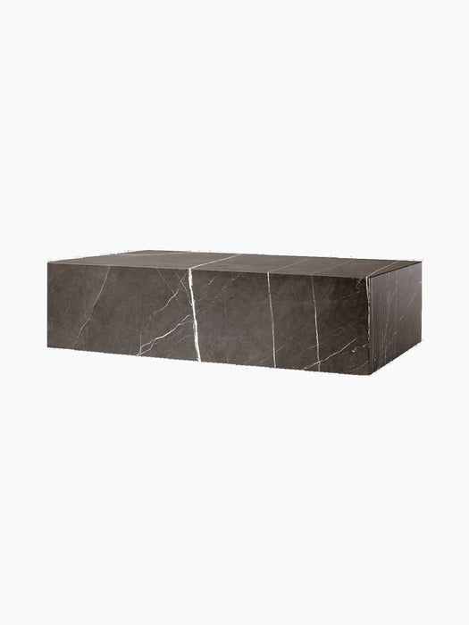 A side-angle view of the Plinth Low, a rectangular block of brown-grey marble with dramatic white veining.