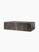 A side-angle view of the Plinth Low, a rectangular block of brown-grey marble with dramatic white veining.