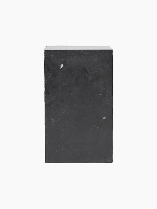 A front-on shot of the dark grey, marble-patterned packaging for the Plinth Tall in black, against a solid black background.