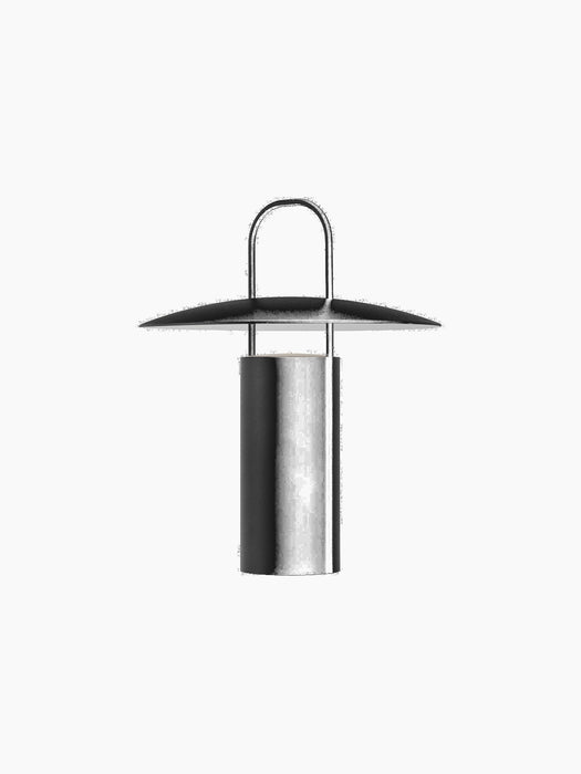 Angled view of the Ray Table Lamp, Portable, in black. The lamp is off, showing its cylindrical base, disc shade, and handle.