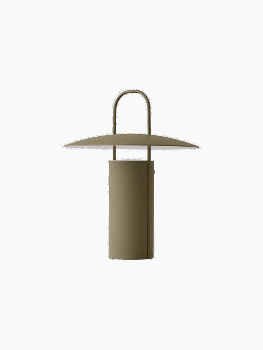 A dusty green Ray Table Lamp, Portable, switched off. The lamp has a cylindrical base, a wide shade, and a handle on top.