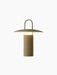 Angled view of the lit Ray Table Lamp, Portable, in dusty green. The lamp has a cylindrical base, a wide shade, and a handle.
