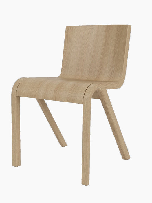 A Ready Dining Chair in natural oak from a side angle on a black background, highlighting its continuous curved form.
