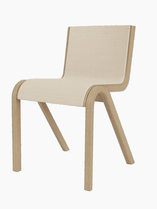 A three-quarter view of the Ready Dining Chair, Front Upholstered, with a natural oak frame and light, textured upholstery.
