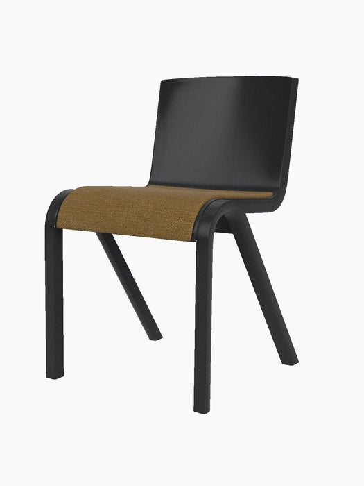 A side-angle view of the Ready Dining Chair, featuring a black painted oak frame and a golden-brown bouclé upholstered seat.