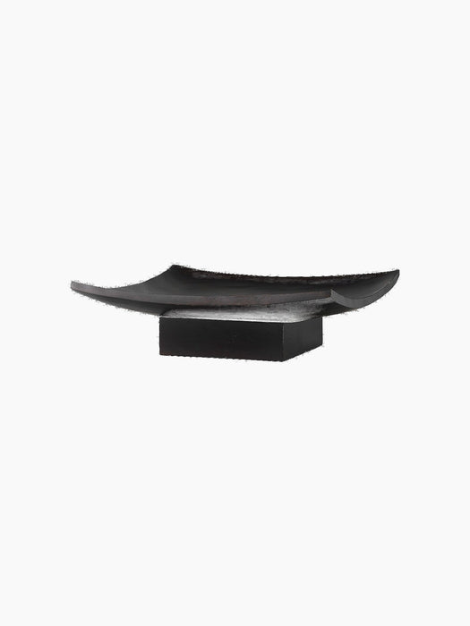 Angled view of the Releve Platter in black wood. The long, sculptural platter has curved, upturned edges and a solid base.