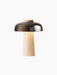 The Reverse Table Lamp, Portable, switched on, with a conical travertine base and a curved, bronzed aluminium shade.
