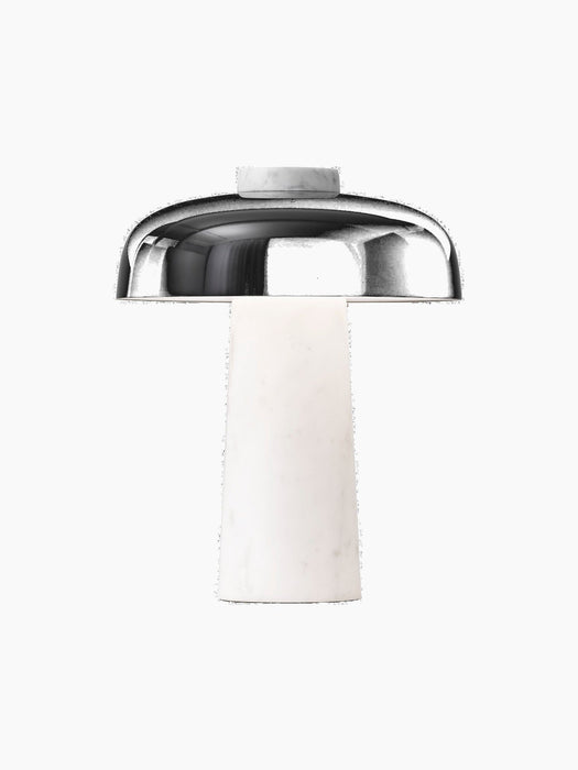 The Reverse Table Lamp with a white marble base and a glossy black shade, shown illuminated against a plain black background.