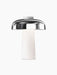 The Reverse Table Lamp with a white marble base and a glossy black shade, shown illuminated against a plain black background.
