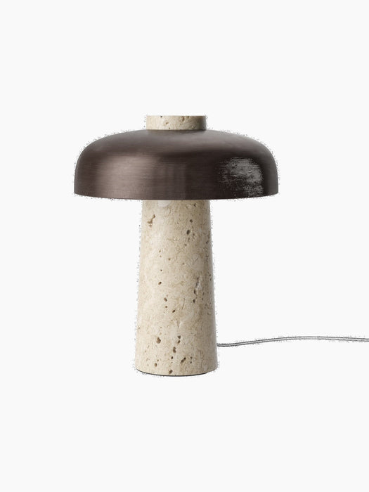 An angled view of the Reverse Table Lamp, showing its textured travertine stone base and smooth, bronzed aluminium shade.