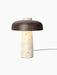 Front view of the Reverse Table Lamp with its lit, conical travertine base and a wide, curved bronzed aluminium shade.