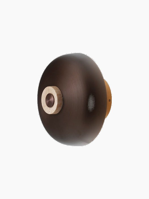 An angled view of the Reverse Wall Lamp against a black background, with bronzed aluminium shade and travertine dimmer.