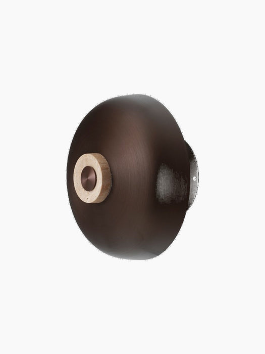 Angled view of the Reverse Wall Lamp, highlighting its bronzed aluminium shade and travertine dimmer.