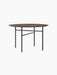 An angled view of the Snaregade Dining Table, Round, featuring a dark stained oak top and a geometric black steel base.