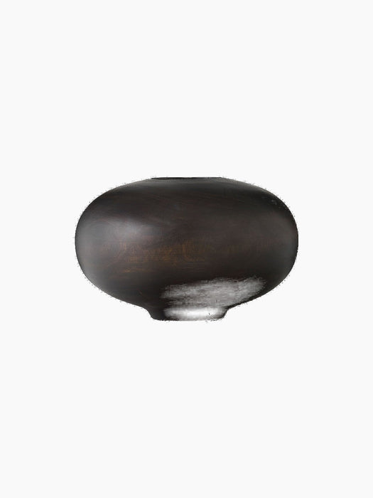 Front view of the Surround Vase, a low, rounded vessel crafted from dark stained wood, against a solid black background.