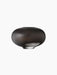 Front view of the Surround Vase, a low, rounded vessel crafted from dark stained wood, against a solid black background.
