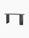 The Eclipse Desk in black lacquered oak from an angle. Asymmetrical design with a curved top, a flat and a cylindrical leg.