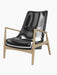 A three-quarter view of The Seal Lounge Chair, High Back, with sleek black leather upholstery and natural oak frame.