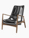 A three-quarter view of The Seal Lounge Chair, High Back, with smooth black leather upholstery and a walnut wood frame.