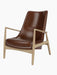 Studio shot of The Seal Lounge Chair, High Back. The chair has a natural oak frame and is upholstered in dark brown leather.